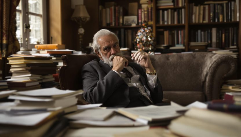 Pensive elderVieil homme pensif dans un bureau rempli de livres.