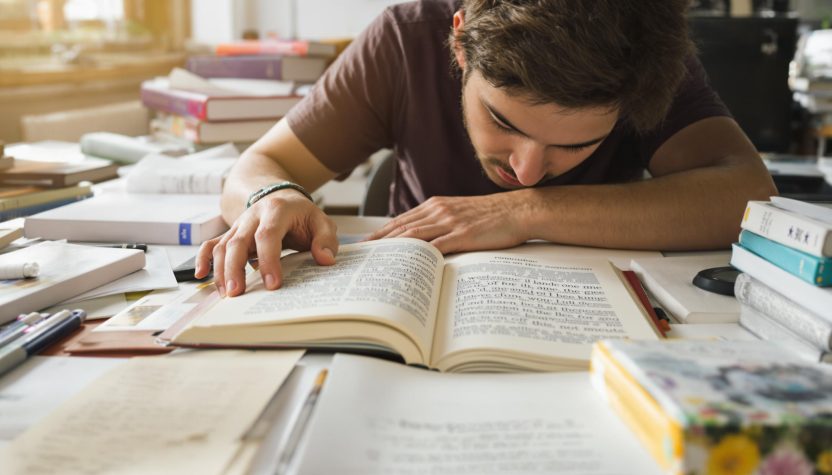 Étudiant fatigué endormi sur un livre au milieu de ses révisions universitaires