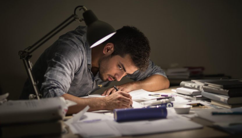 Man studying at desk under lamp