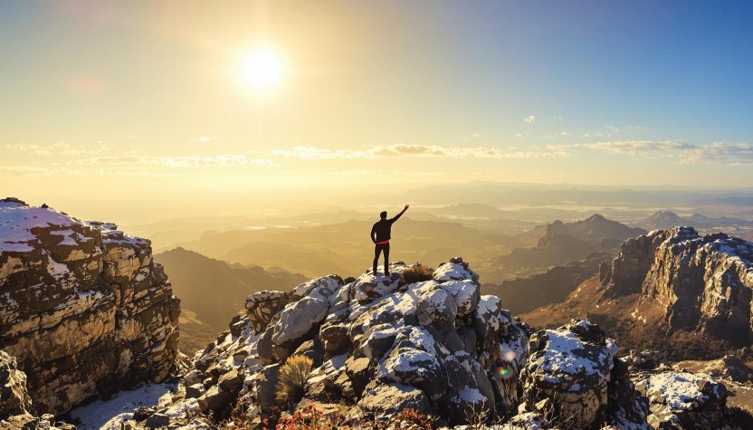 Un homme au sommet d'une montagne au lever du soleil.